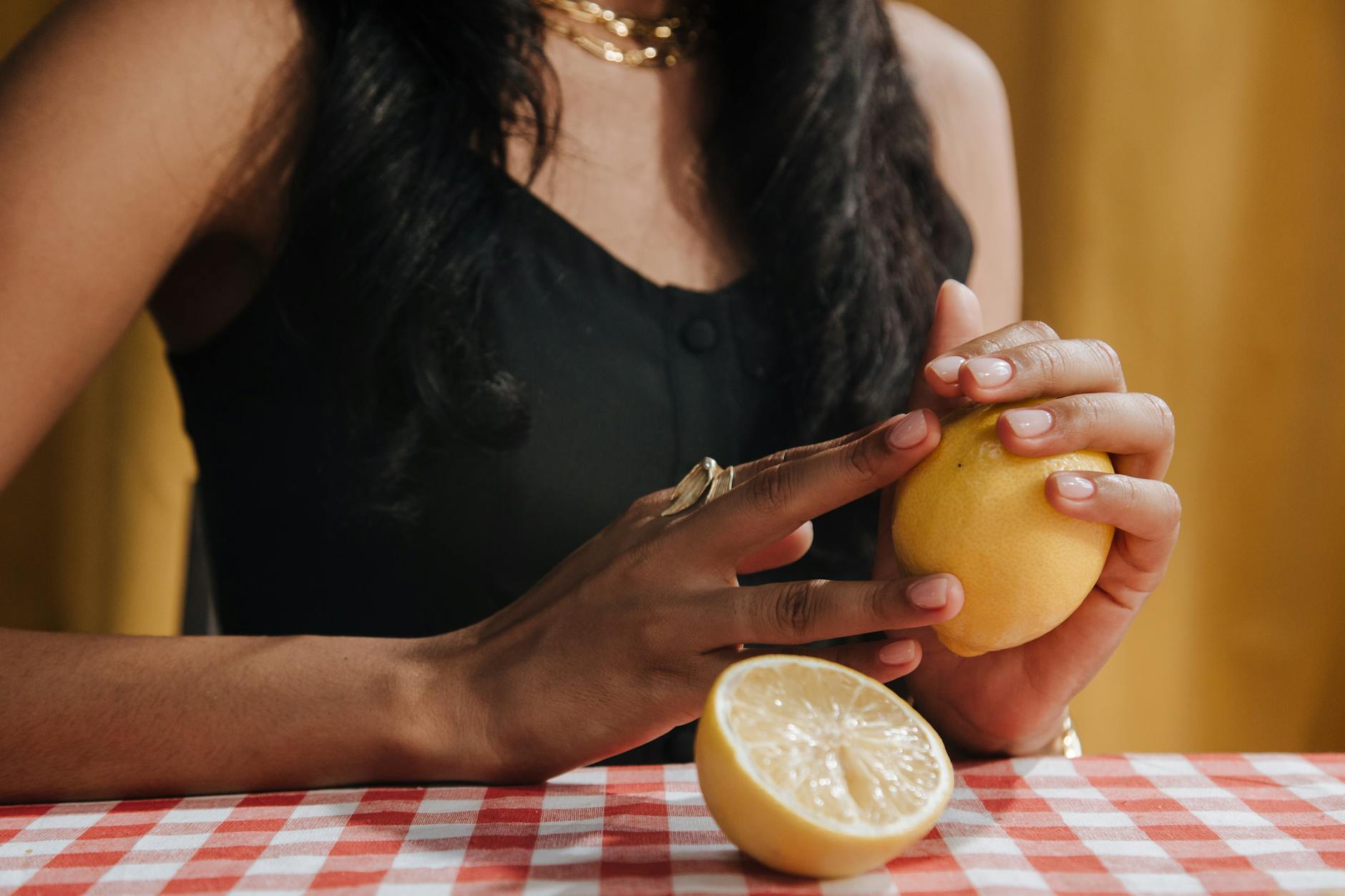 A woman's hands holding a pink vibrator with art books in soft focus, symbolizing intimate exploration and intentional pleasure.