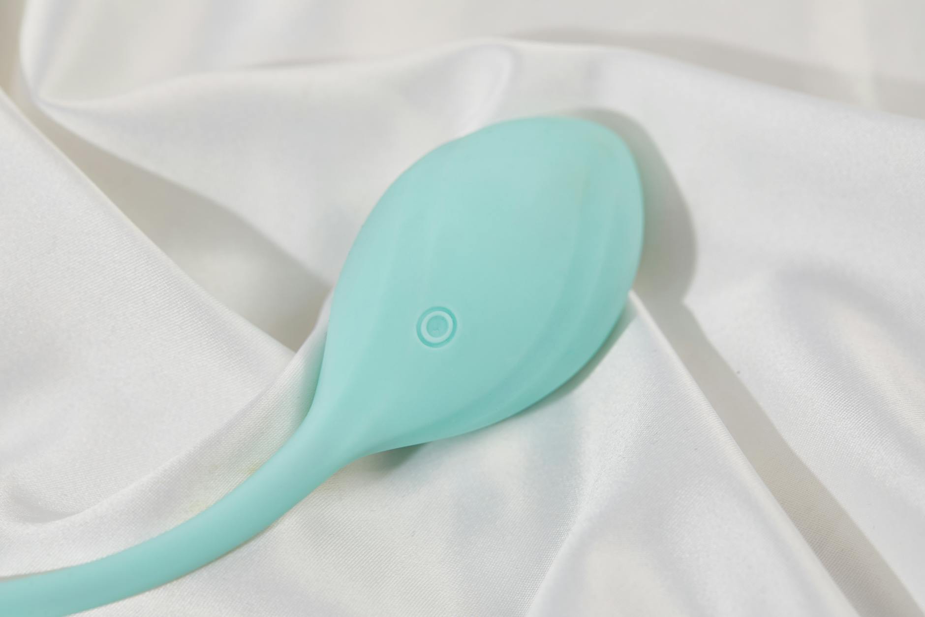 Teal lemon clitoral vibrator on white silk fabric