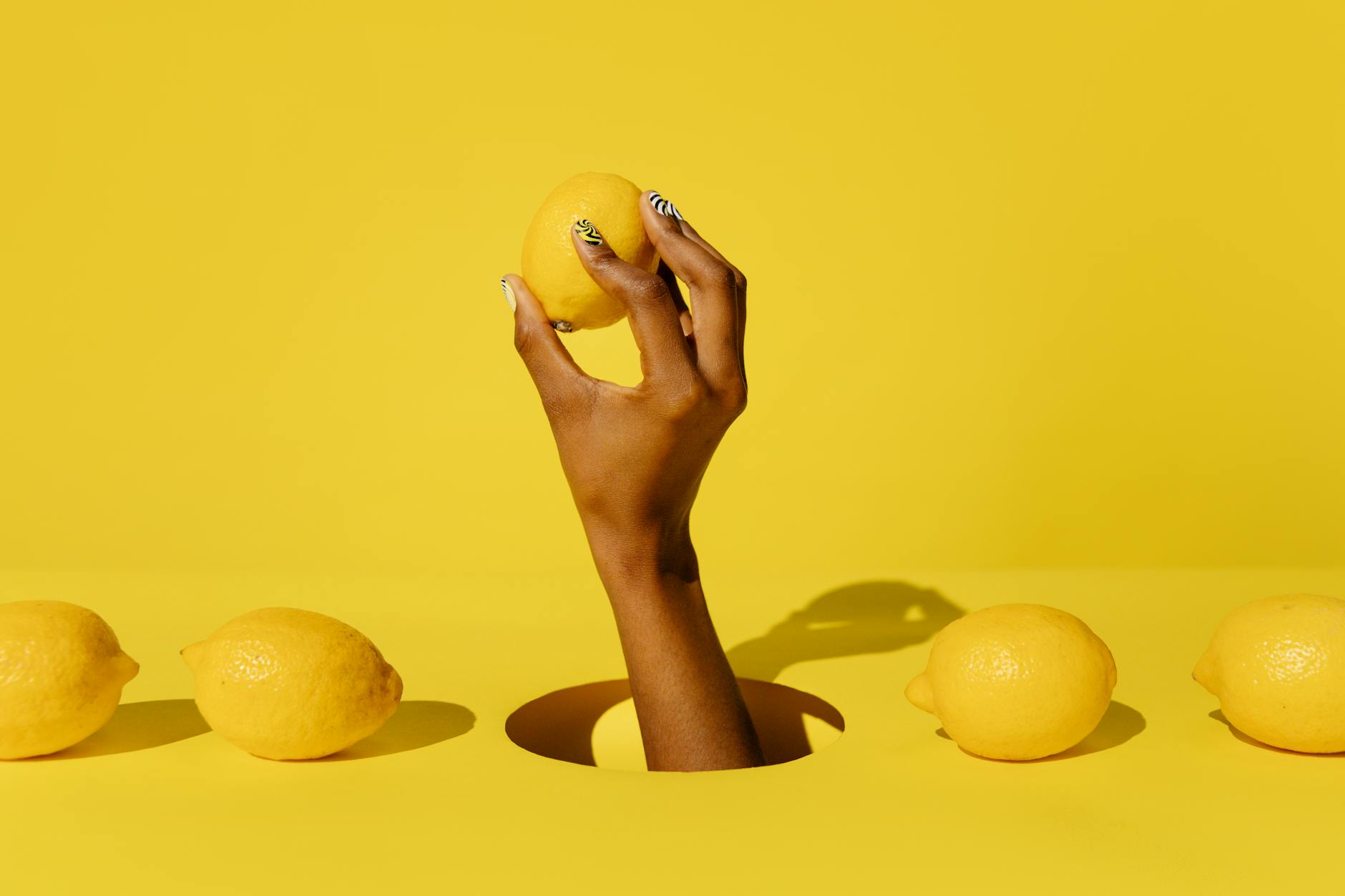 Hand holding a lemon against a vibrant yellow background, symbolizing fresh pleasure and sensory reset