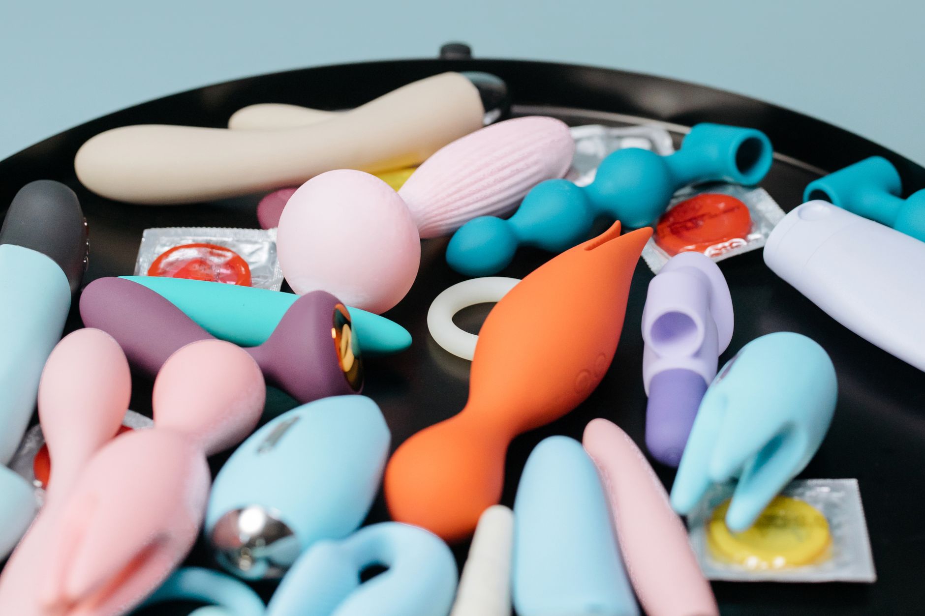 Person holding a blue and pink vibrator, demonstrating comfort and exploration