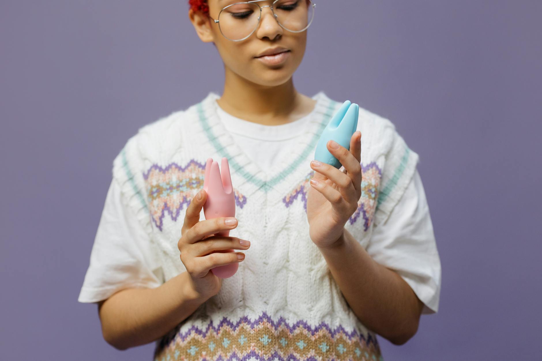 Woman holding vibrators in contemplative manner, thinking about partner communication