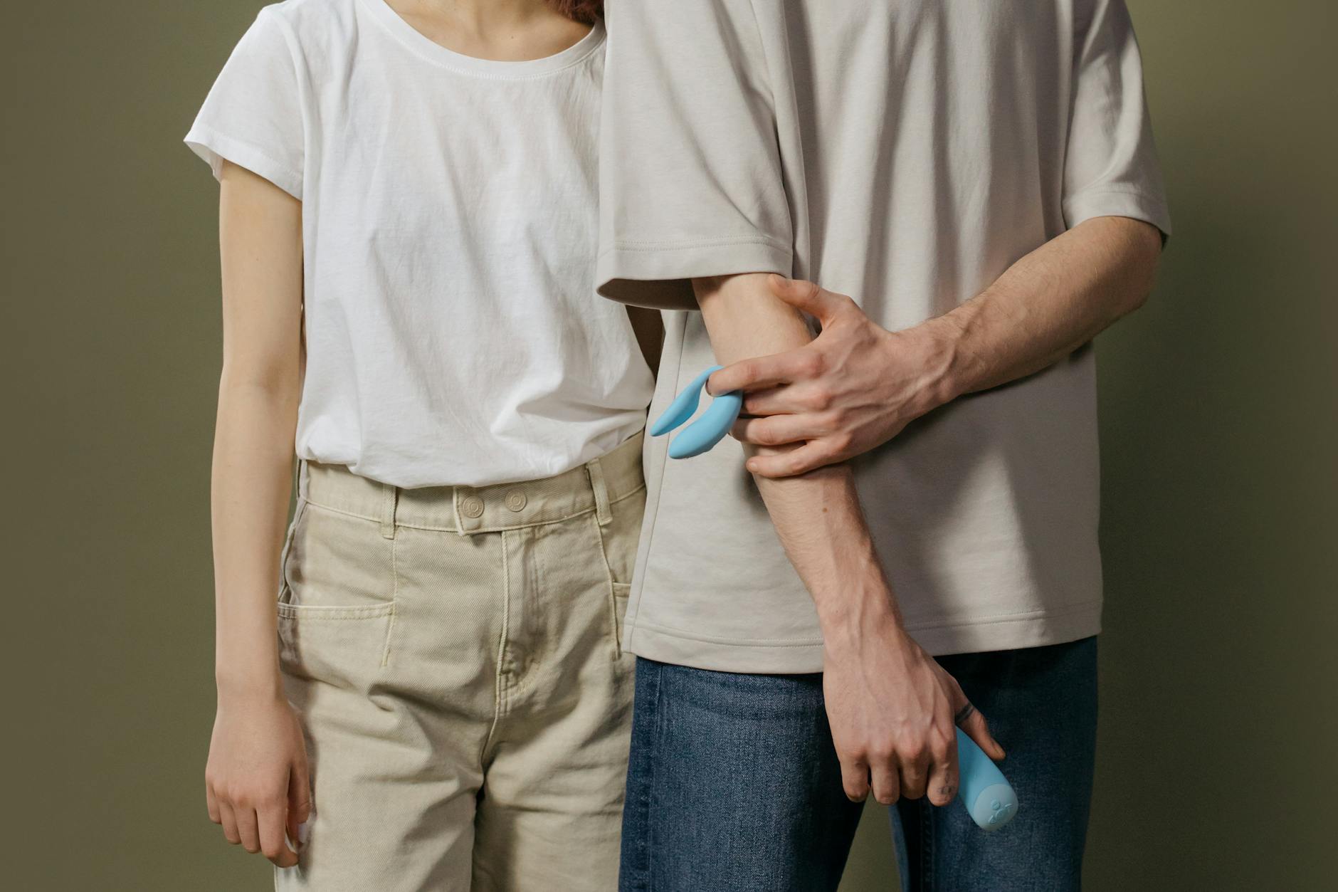 A couple holding a blue vibrator together, representing modern intimacy and connection